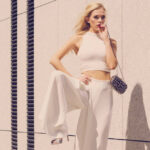 Elegant fashionable woman presenting trendy urban outfit. White crop top and trousers culottes. Outdoor photo session, unusual bizarre pose