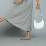 Woman with stylish bag on grey background, closeup