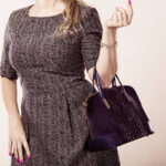 Fashion clothing people concept. Chic woman with black, leather handbag. Female wearing elegant dress.